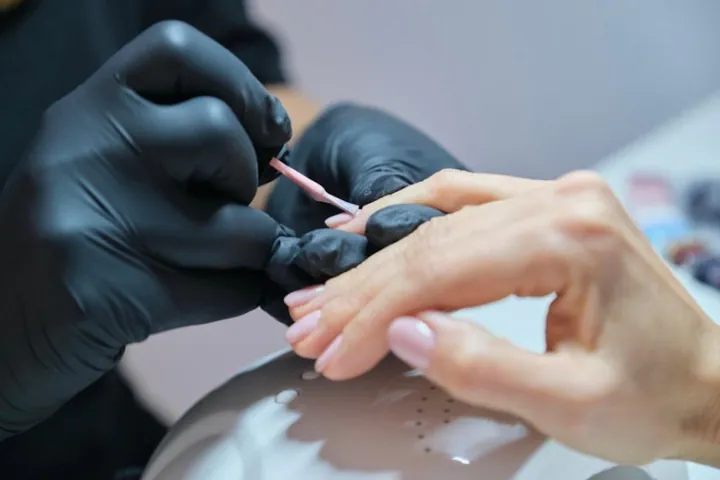 Maniküre mit Handschuhen am Nagelplatz